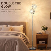 Silver two-head floor lamp glowing beside a bed with the text Double the Glow