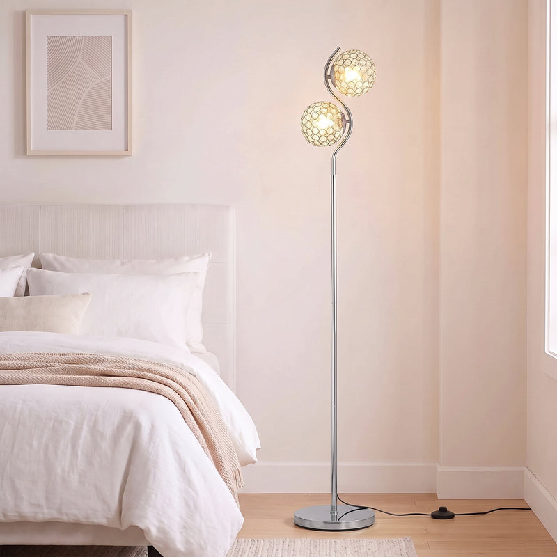 Silver crystal globe floor lamp lit beside a white bed in a bright bedroom