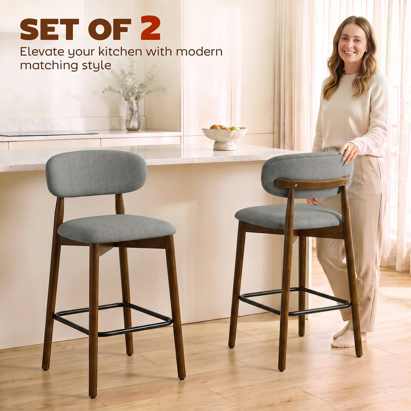 Woman standing in a kitchen beside two grey curved-back bar stools