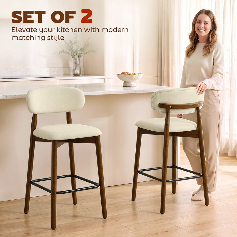 Woman standing in a kitchen beside two beige curved-back bar stools