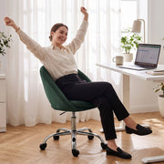 Woman stretching while seated in the dark green desk chair at a desk