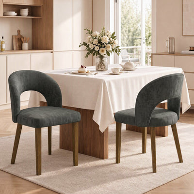 Two dark grey open back dining chairs at a table with a cream tablecloth
