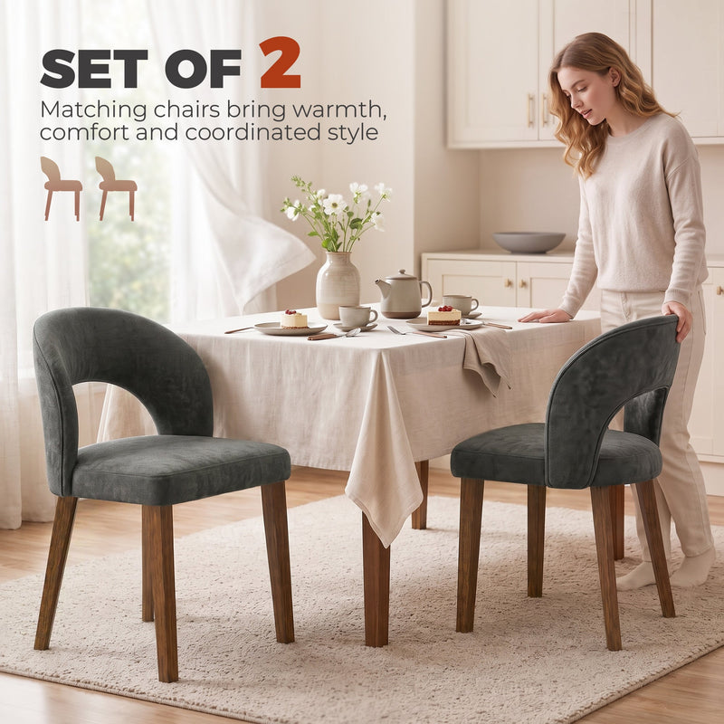 Woman standing beside a dining table set with two dark grey chenille chairs