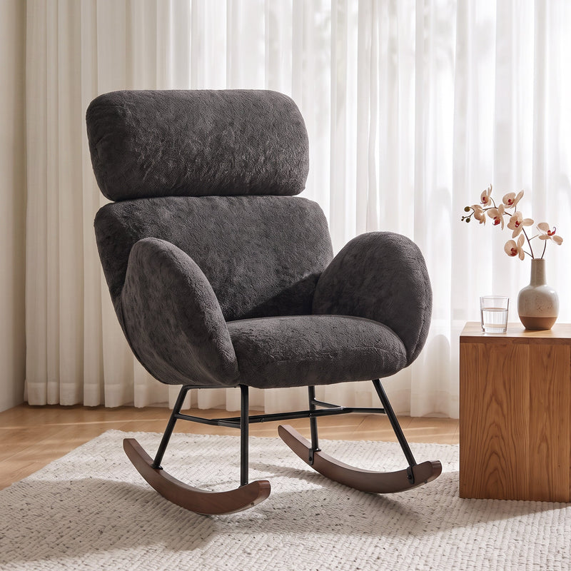 Dark grey velvet rocking chair beside a sheer curtain and side table in a living room