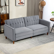 Dark grey velvet sofa bed in a living room with bookshelf and armchair