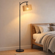 Lit floor lamp beside a bed in a bedroom