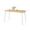 Golden Oak and Cloud White dining table with white tapered steel legs on a plain background