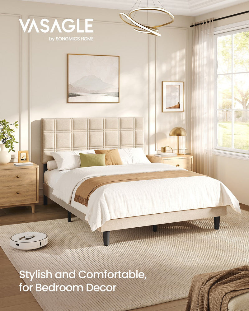 Upholstered double bed in a bright bedroom with a robot vacuum passing under the raised frame