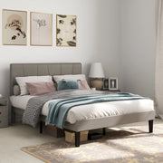 Grey double bed frame in a bedroom with framed prints, a table lamp and a floral rug