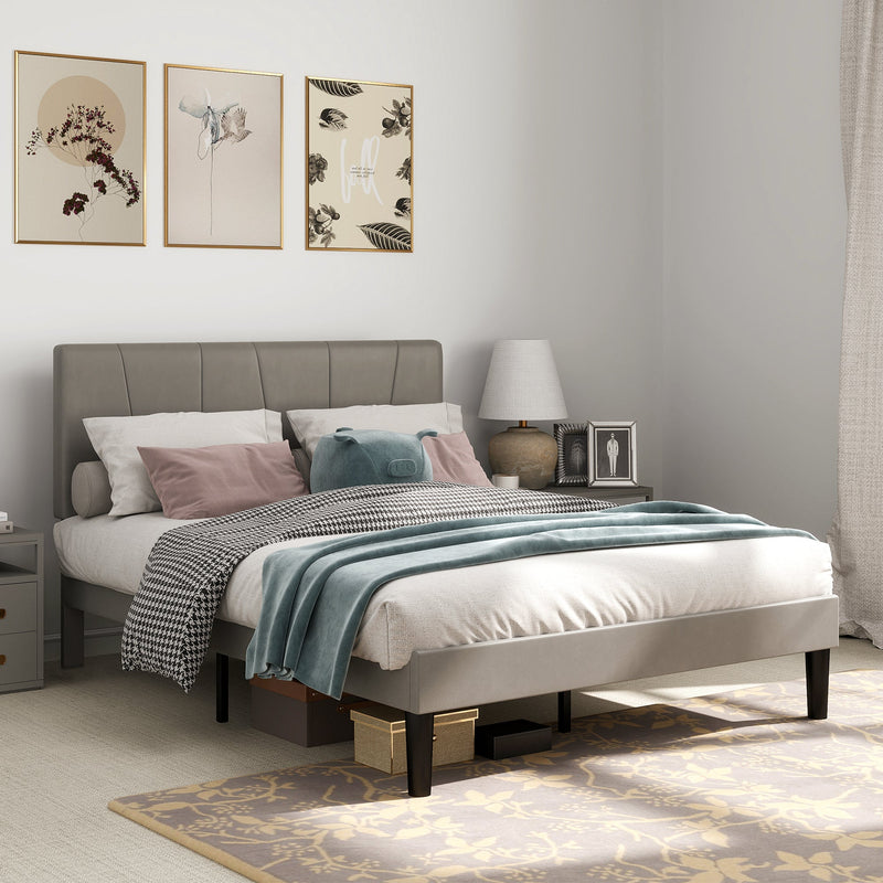Grey double bed frame in a bedroom with framed prints, a table lamp and a floral rug