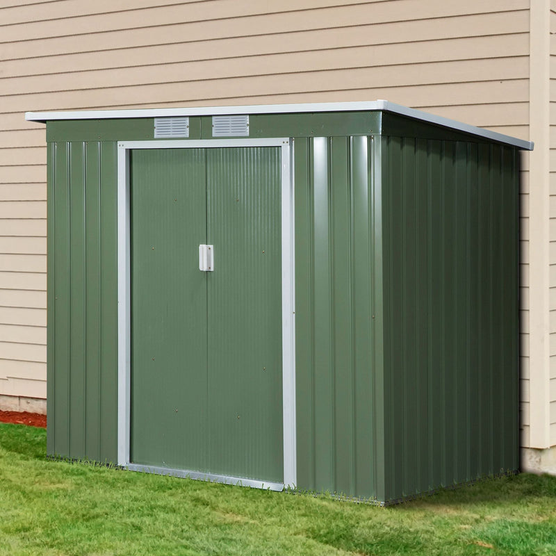 The green metal shed standing on grass against a cream clad house wall, doors closed