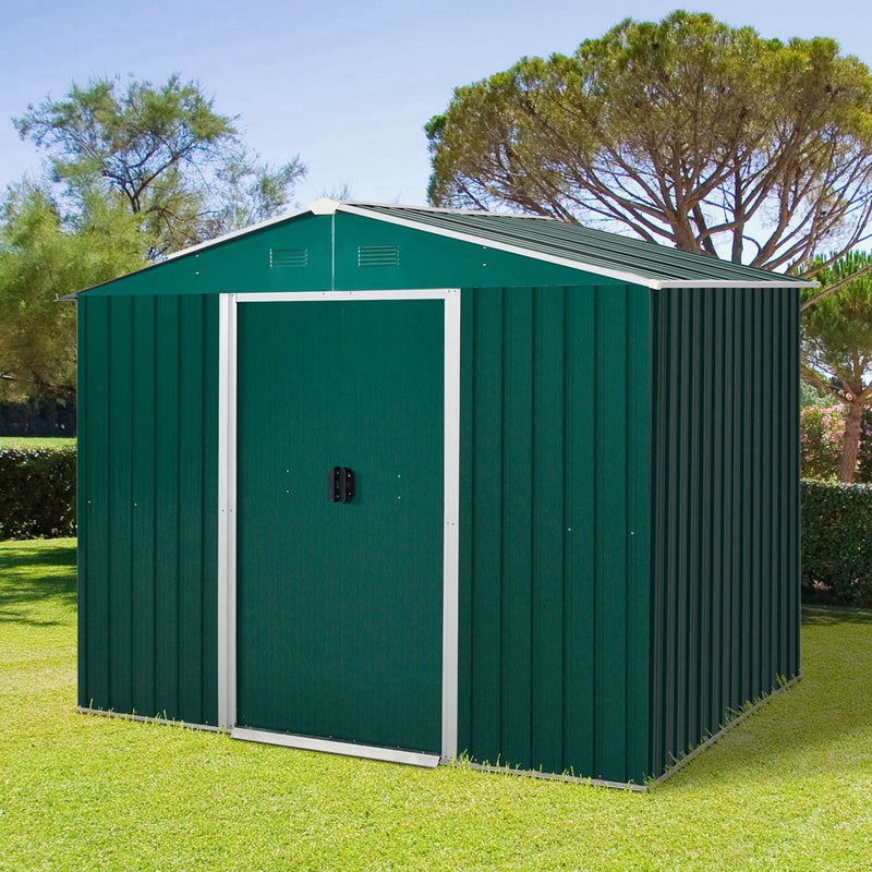 Green 8x6ft metal garden shed with closed double sliding doors standing on a lawn in front of tall trees