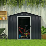 Dark grey metal shed against a weathered fence with the door open and a bicycle and spade stored inside