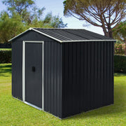 Dark grey 8x6ft metal garden shed with closed sliding doors on a lawn in front of tall trees