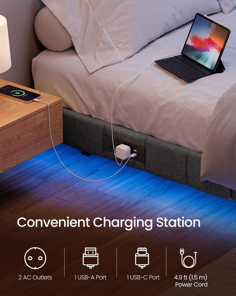 Close-up of the side charging station with a laptop and a phone plugged in beside the bed