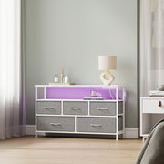 Dresser in a green bedroom with purple LED lighting and a table lamp on top