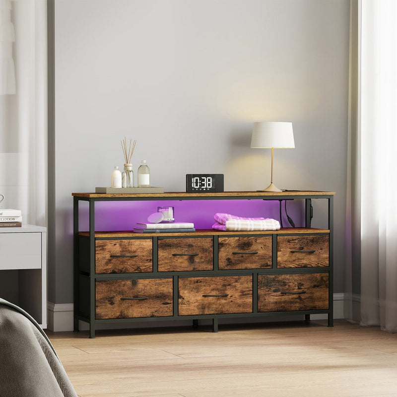 Dresser in a bedroom with purple LED lighting, an alarm clock and a table lamp on top