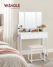 White vanity table with tri-fold mirror and stool styled beside a bed