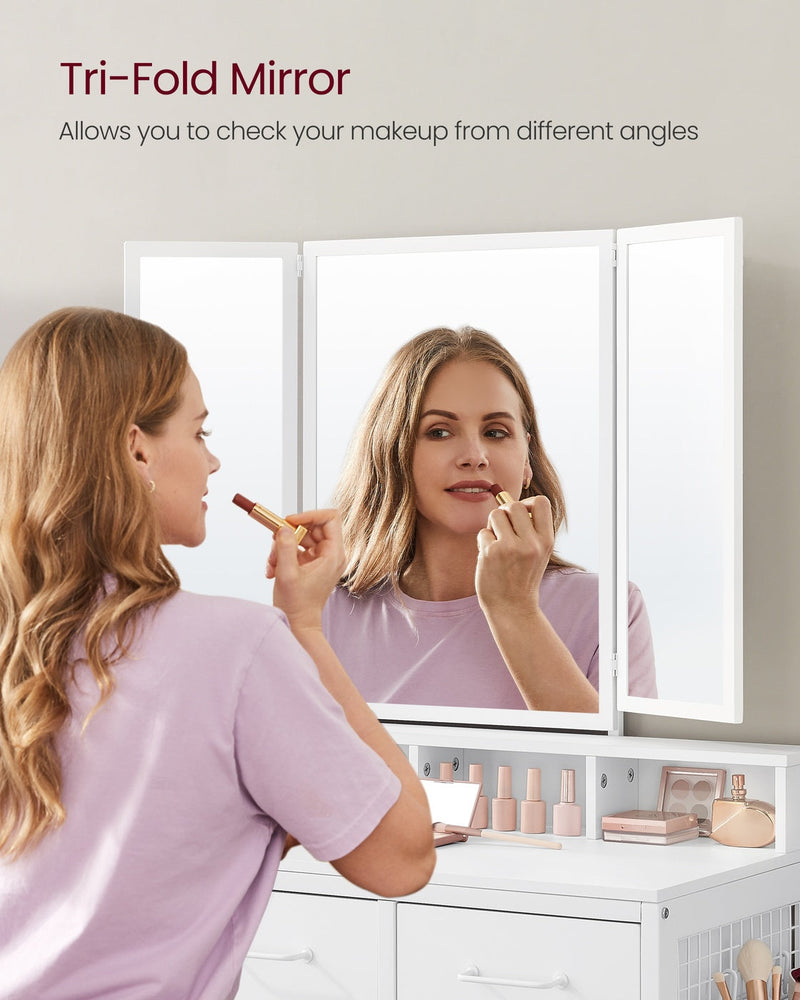 Woman applying lipstick at the white dressing table using the tri-fold mirror