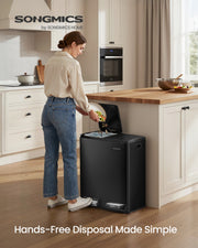 Woman in a kitchen tipping food scraps into the open left compartment of the black bin