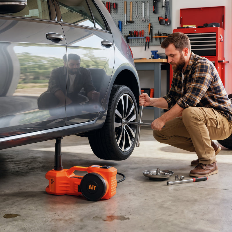 Man removing a wheel in a garage with the car lifted on the electric jack