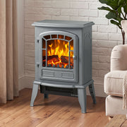 Grey electric fireplace stove beside a curtained window and armchair