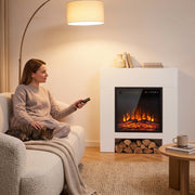 Woman holding the remote beside the white fireplace suite with logs stored underneath