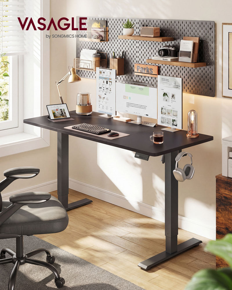 Standing desk in a home office with a pegboard wall, monitors and headphones on the side hook