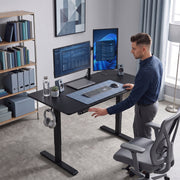 Black standing desk in a home office with a person adjusting the height while standing