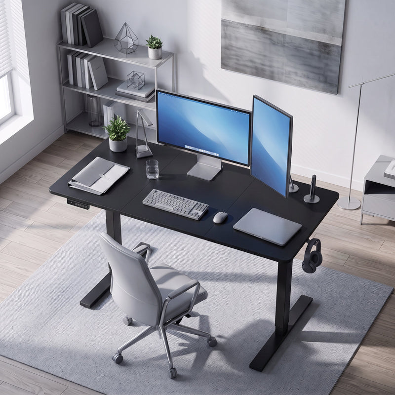 Black standing desk in a home office viewed from above with a desk chair and shelving