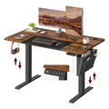 Songmics electric standing desk in rustic brown and black, studio view with dual monitors and storage bag