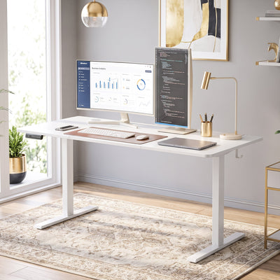 Standing desk at sitting height in a home office with two monitors and a desk lamp