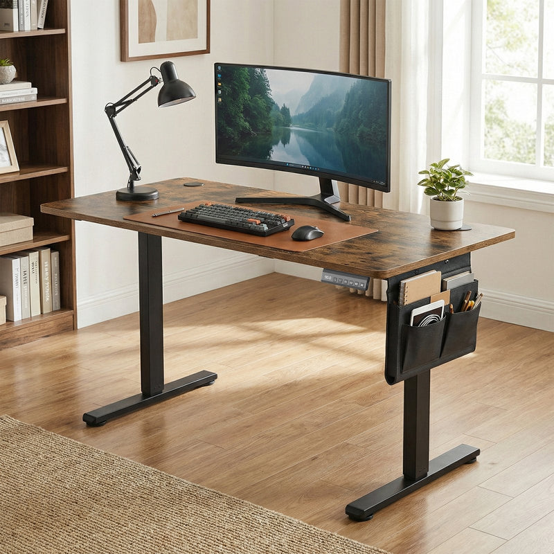 Standing desk in a home office with a curved monitor, keyboard and desk lamp