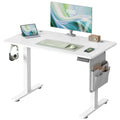 White electric standing desk with a monitor, keyboard, side storage pocket and headphone hook