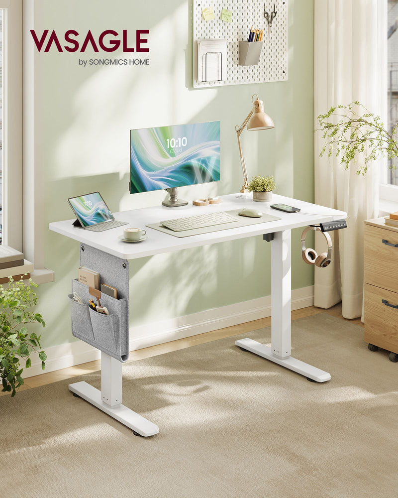 Vasagle white standing desk in a home office with a pegboard, desk lamp and plants