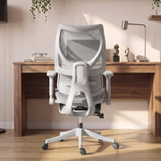 Grey mesh office chair seen from behind facing a wooden desk with a lamp