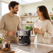 Couple standing at a kitchen island holding coffees beside the espresso machine