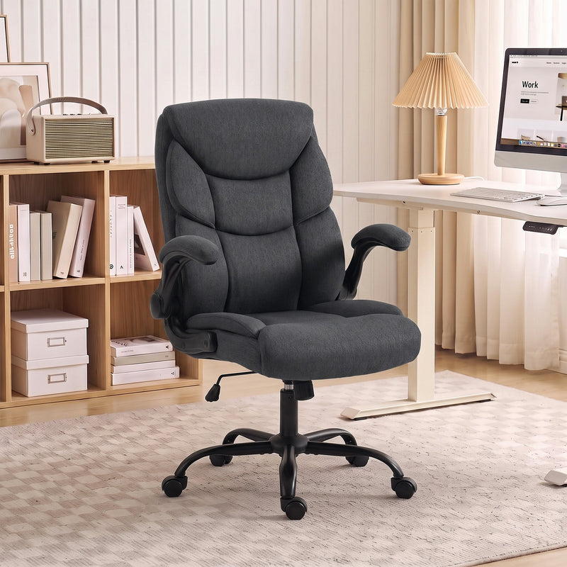 Dark grey office chair at a light home office desk beside shelves and a lamp