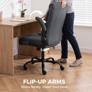 Dark grey chair with a flip-up armrest raised and the chair sliding under a wooden desk