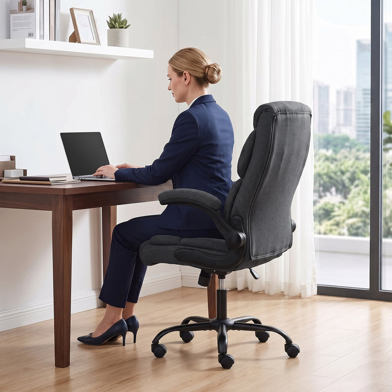 Woman in a navy suit working on a laptop in the dark grey office chair
