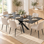 Black marble effect table laid for a meal with cream chairs beside a sideboard