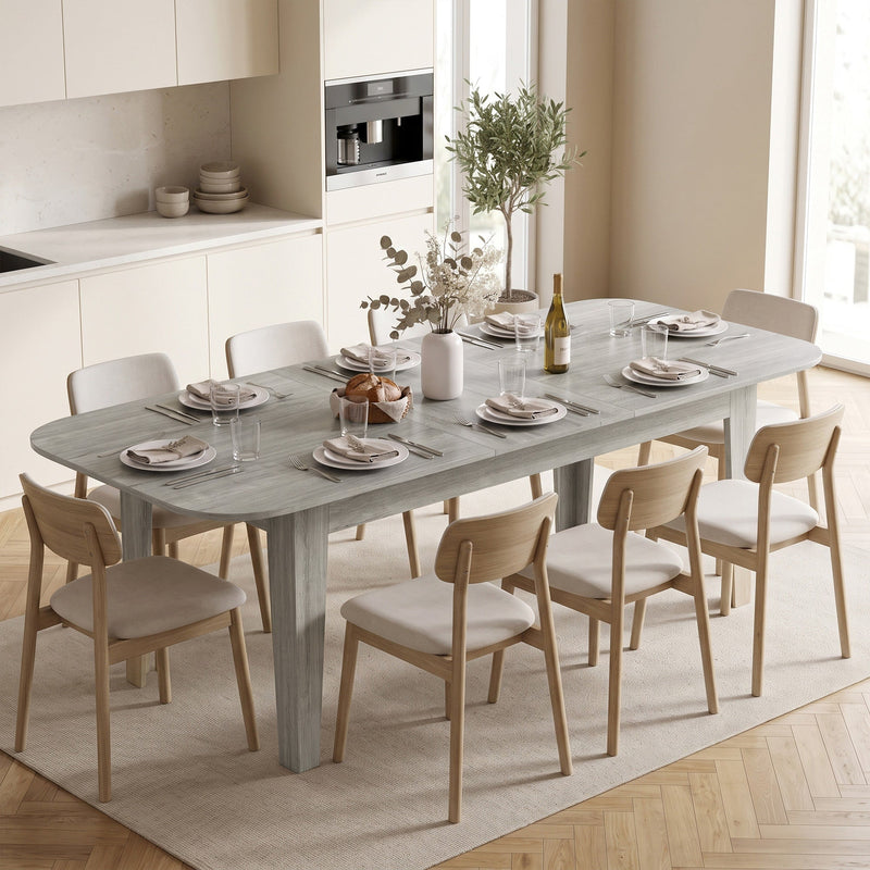Extendable dining table laid for a meal with 6 chairs in a bright kitchen