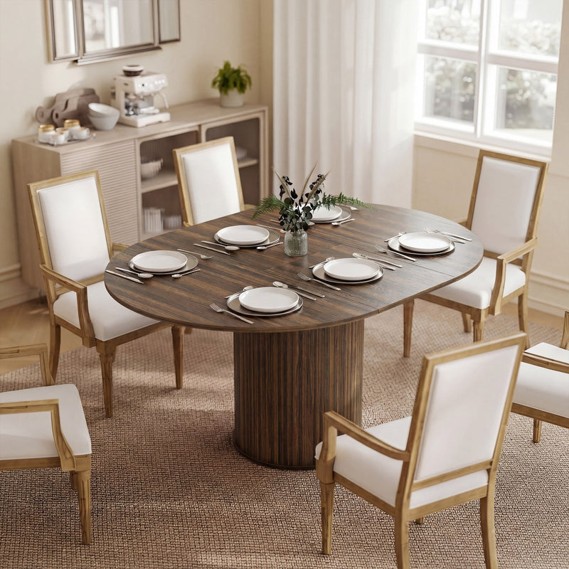 Walnut oval dining table laid for dinner with upholstered chairs in a bright dining room