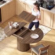 Woman lowering an extension board into the opened walnut table in a kitchen