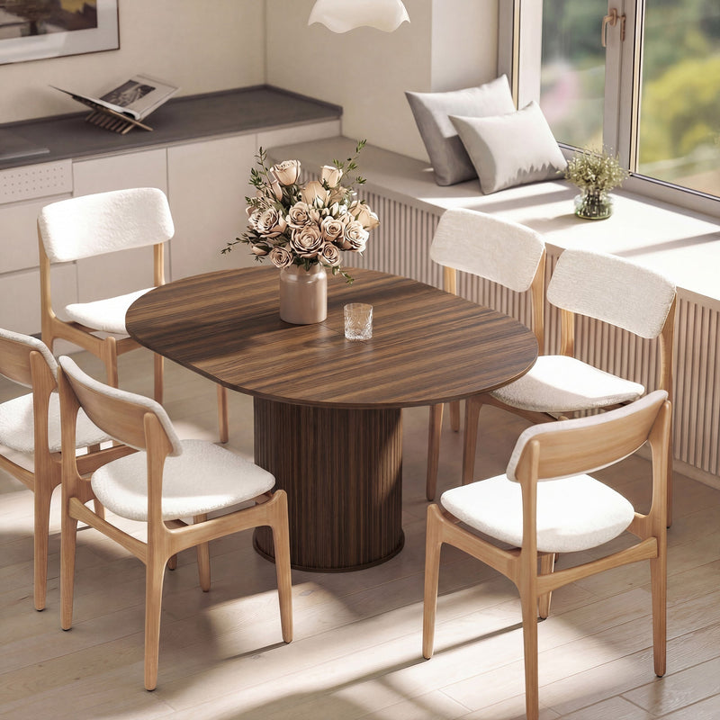 Extended oval walnut table with six cream-cushioned chairs beside a window and a vase of roses