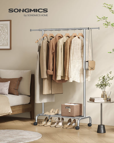 Songmics branded silver clothes rail styled in a bedroom with hanging clothes and shoes