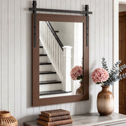 Dark brown farmhouse mirror above a hallway console beside a staircase