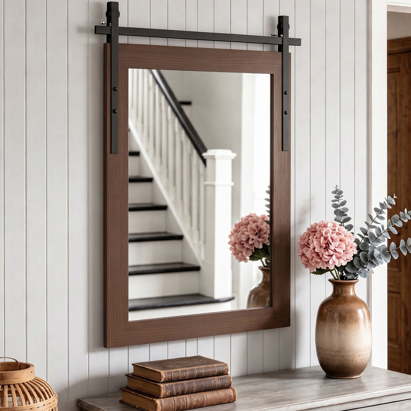 Dark brown farmhouse mirror above a hallway console beside a staircase