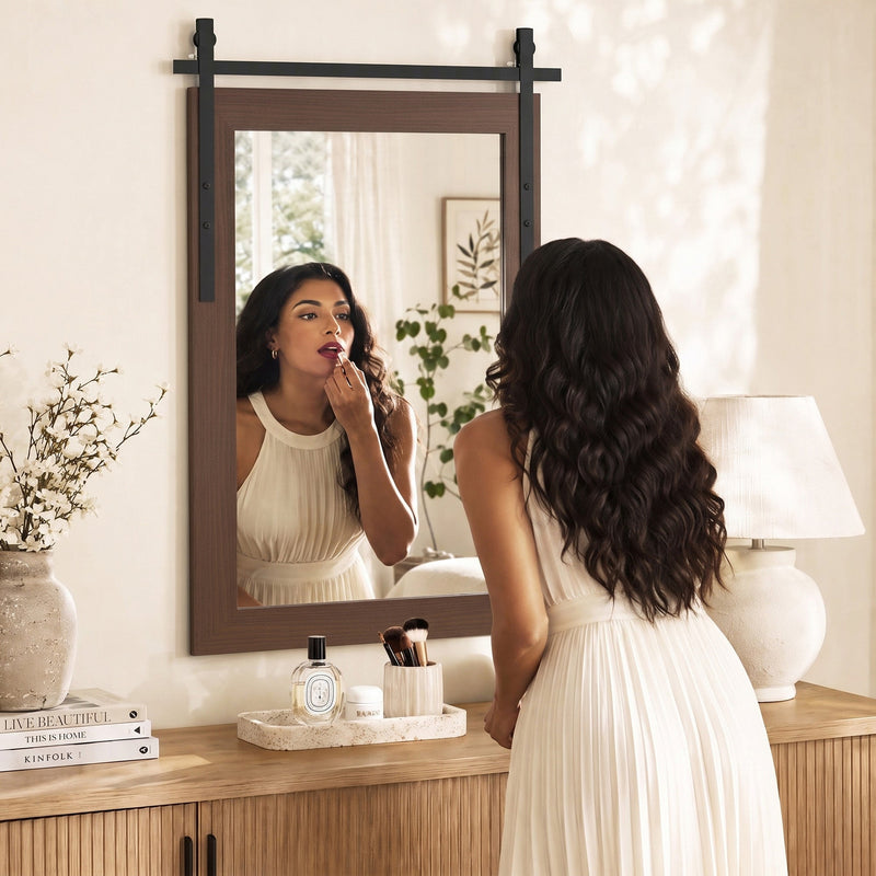 Woman applying lipstick in the wall mirror above a wooden sideboard