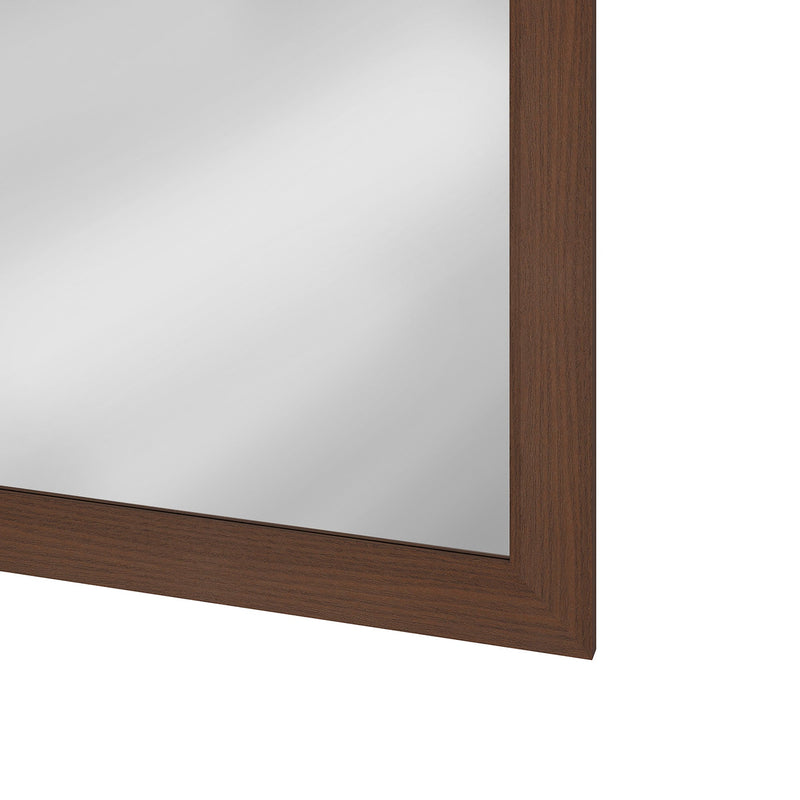 Close-up of the mirror glass edge against the dark brown frame